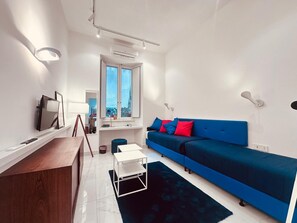 A modern living room with a blue sofa, a small white table, and a dark rug. - NEW! Nice apartment 2 steps from villa Borghese and Spanish Steps (Roma)