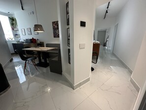 Een moderne keuken met een eethoek, marmeren vloeren en uitzicht op de aangrenzende woonkamer.