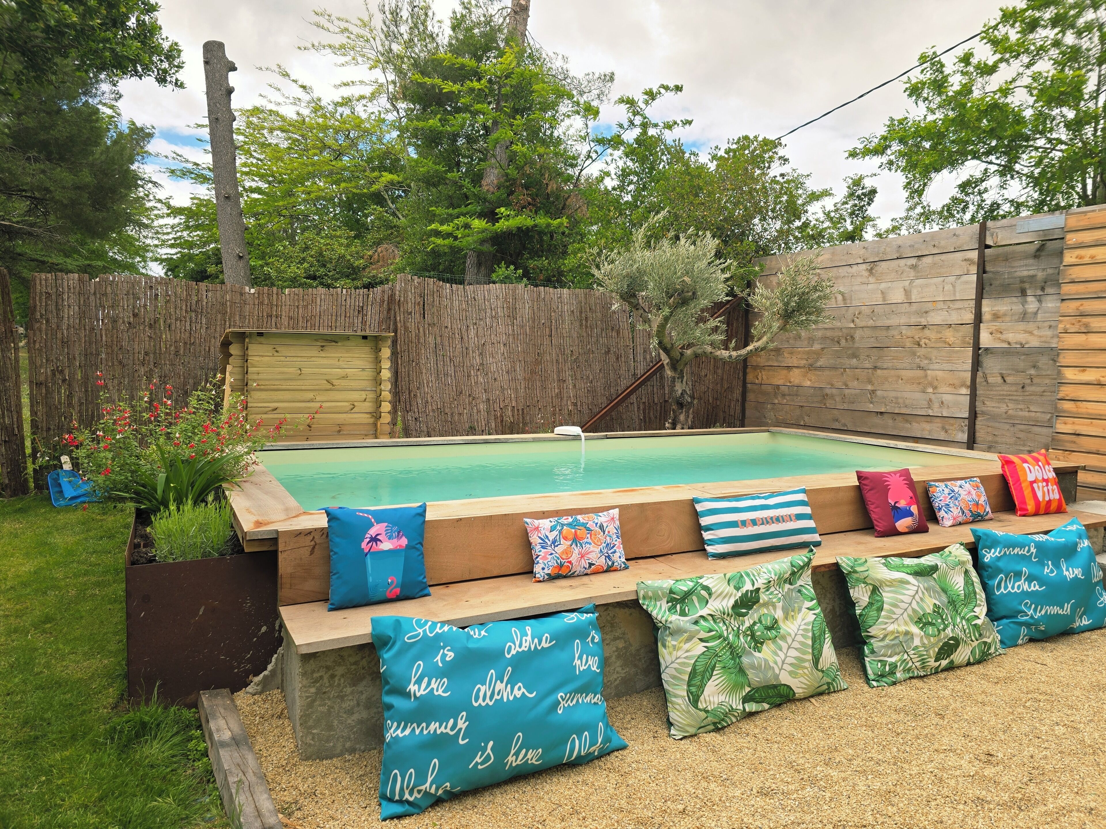 A backyard with a swimming pool, wooden deck, and a wooden fence.