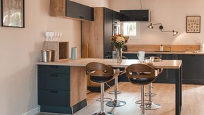 Een moderne keuken met een houten kookeiland, barstoelen en een eettafel.