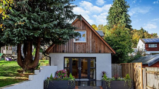 A small wooden house with a modern design, a large tree in the front, and a fenced backyard. - 1 Bed in Strathpeffer (oc-h30077) (Strathpeffer)