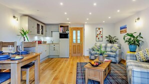 A modern living room with a sofa, coffee table, and dining area. - 1 Bed in Strathpeffer (oc-h30077) (Strathpeffer)