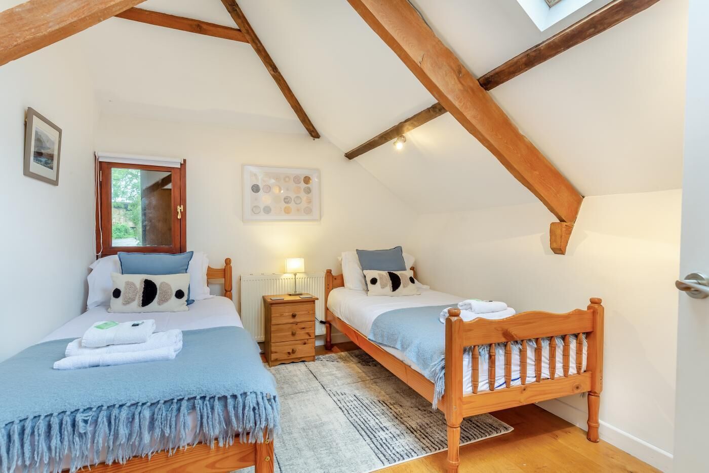 Une chambre à coucher avec deux lits en bois, une table de chevet, un radiateur et une fenêtre donnant sur un beau paysage.