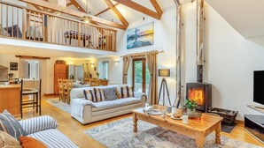 A spacious living area with a high ceiling, wooden beams, a fireplace, and a dining area. - 4 Bed in Torpoint (oc-m30122) (Downderry)