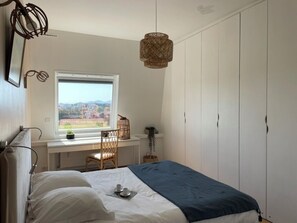 A bedroom with a bed, a desk, and a window with a view. - Apartment Biarritz le phare view golf and Ocean, near beach and city center (Biarritz)