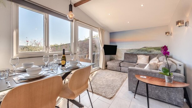 A modern living room with a grey sofa, a small round table, and a TV mounted on the wall. - 2 Bed in Llangain (oc-g30185) (Llangain)