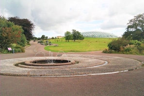 A circular water feature with a fountain in the center, surrounded by a gravel path.