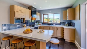 Een moderne keuken met een groot kookeiland, houten kastjes en uitzicht op de omgeving.