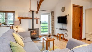 Een gezellige woonkamer met een bank, een salontafel, een open haard, een televisie en een deur naar een balkon.
