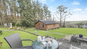A glass table with chairs and a house in the background. - 1 Bed in Stibb (oc-c30250) (Stibb)