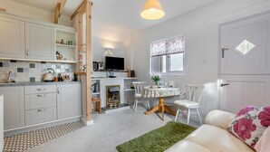 A modern kitchen with white cabinets, a dining area with a floral tablecloth, and a cozy seating area with a green rug. - 1 Bed in Stibb (oc-c30250) (Stibb)
