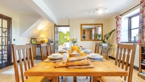 Un comedor con una mesa de madera dispuesta para seis personas, rodeada de sillas de madera con asientos acolchados.