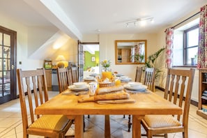 Un comedor con una mesa de madera dispuesta para seis personas, rodeada de sillas de madera con asientos acolchados.