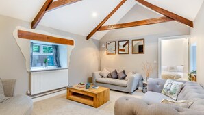 A loft-style living room with exposed wooden beams, a sofa, a coffee table, and a view through a window. - 3 Bed in Yeolmbridge (oc-t30293) (Werrington)