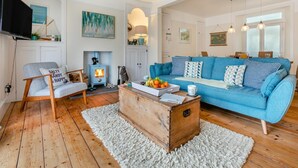 Ein gemütliches Wohnzimmer mit einem blauen Sofa, einem Holztisch, einem blauen Sessel und einem Kamin.