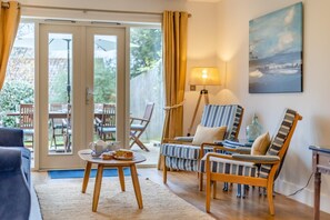 A cozy living room with a sofa, two striped armchairs, a coffee table with a cake, and a painting on the wall. - 4 Bed in Blakeney (oc-m30326) (Blakeney)