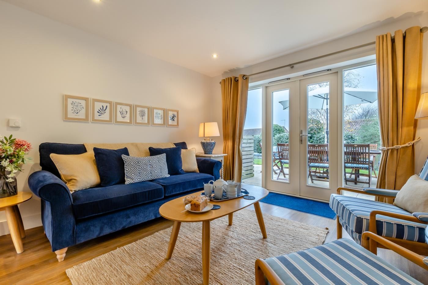 A living room with a blue sofa, a coffee table, and a view of the outdoors through large glass doors.