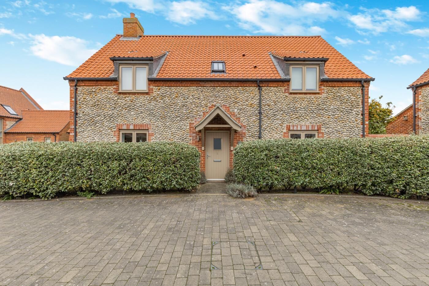 A stone house with a tiled roof, a central entrance, and two windows on the upper floor.