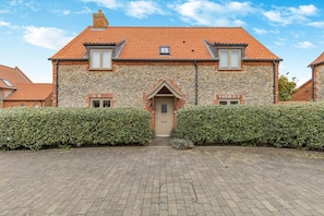 A stone house with a tiled roof, a central entrance, and two windows on the upper floor. - 4 Bed in Blakeney (oc-m30326) (Blakeney)