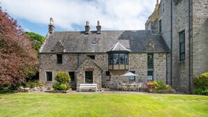 A stone building with a garden in front, a bench, and a table with chairs. - 4 Bed in Cardross (oc-t30303) (Cardross)