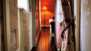 A narrow hallway with stone walls, a wooden floor, and a lamp in the distance. - 4 Bed in Cardross (oc-t30303) (Cardross)