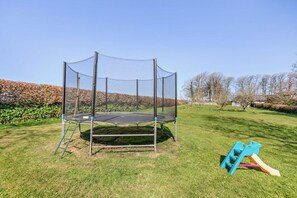 A trampoline with a safety net enclosure in a grassy area. - 2 Bed in North Tamerton (oc-t30362) (North Tamerton)