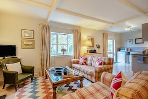 A living room with a sofa set, a coffee table, a television, and a kitchen in the background. - 2 Bed in North Tamerton (oc-t30362) (North Tamerton)