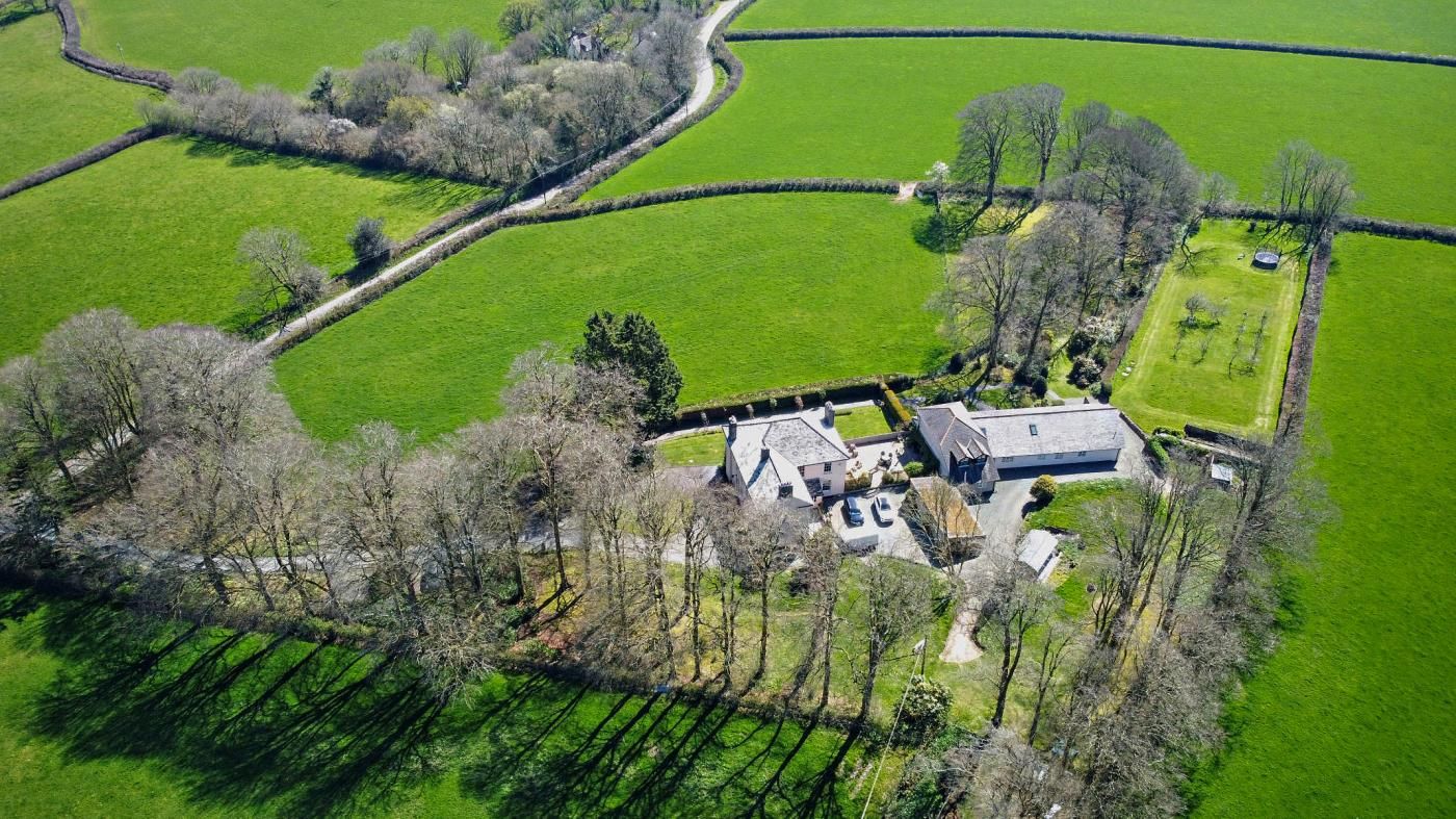 A large estate with multiple buildings, surrounded by green fields and trees.