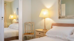 A hotel room with a bed, a chair, a nightstand with a lamp, and a mirror on the wall. - 2 Bed in North Tamerton (oc-t30362) (North Tamerton)