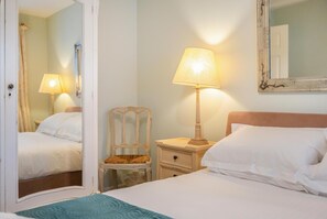 A hotel room with a bed, a chair, a nightstand with a lamp, and a mirror on the wall. - 2 Bed in North Tamerton (oc-t30362) (North Tamerton)