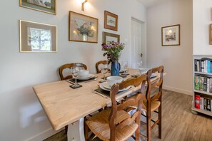 Comedor con mesa de madera dispuesta para cuatro personas, rodeada de sillas de madera con asientos de mimbre.