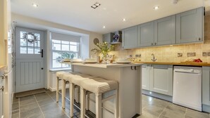 A modern kitchen with grey cabinets, a built-in dishwasher, and a window overlooking a scenic view. - 2 Bed in Fowey (oc-r30265) (Fowey)
