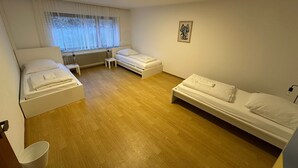 A room with two single beds, a small table, a radiator, and a window with sheer curtains. - Vacation apartment at the clinic Worms (Worms)