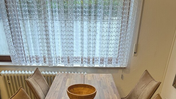 A wooden dining table with a central bowl, surrounded by six brown leather chairs. - Vacation apartment at the clinic Worms (Worms)