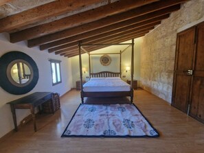 A bedroom with a four-poster bed, a wooden bench, a circular mirror, and a stone wall. - Villa Son Felip (Palma)