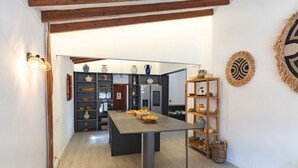 Una cucina moderna con isola centrale, scaffali in legno con ceramiche e decorazioni murali rustiche.