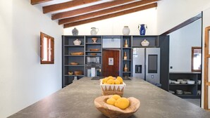 Una cucina con un lungo bancone, travi in legno ed scaffali pieni di utensili da cucina.