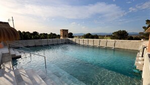 Una piscina con acqua cristallina, struttura in cemento e vista sulle montagne lontane.