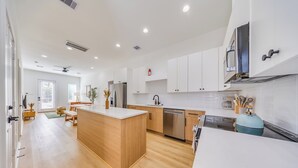 A modern kitchen with white cabinets, a wooden island, stainless steel appliances, and a blue gas stove. - Scandinavian Escape • Pergola • Pool • Fire Pit (Houston)