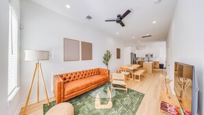 A spacious living area with a sofa, a dining table, and a TV. - Scandinavian Escape • Pergola • Pool • Fire Pit (Houston)