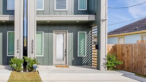 A modern two-story residential building with a flat roof, large windows, and a visible front door. - Scandinavian Escape • Pergola • Pool • Fire Pit (Houston)