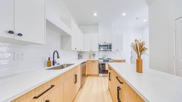 A modern kitchen with white cabinetry, a stainless steel sink, and a microwave.