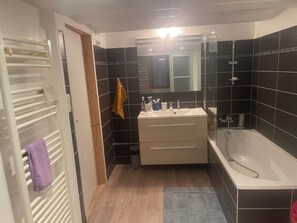 A bathroom with a white sink, a mirror, a bathtub, and a towel rack. - Room for rent in a private home (Caluire-et-Cuire)