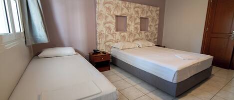 A hotel room with two beds, a nightstand, and a wooden door.