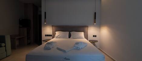 A modern hotel room with a neatly made bed, two bedside tables, and a built-in bench.