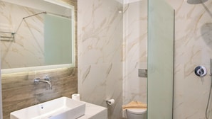 A modern bathroom with a large mirror, a rectangular sink, a glass shower enclosure, and a toilet. - Elektra Hotel (Paleros)