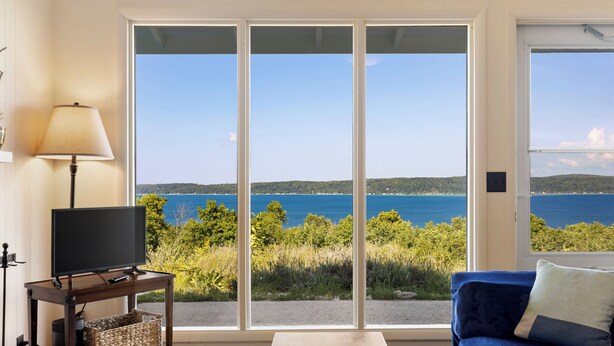 Una habitación con un amplio ventanal corredero que da a una vista panorámica de un lago y colinas.