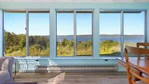 Una habitación con ventanas amplias que dan a un lago y un bosque.