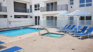 Ein Poolbereich mit zwei Pools, blauen Liegestühlen und Sonnenschirmen.