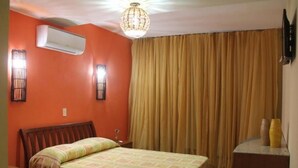 A hotel room with a bed, a wooden headboard, an air conditioner, a chandelier, and a curtain. - Pousada Gitana (Parnamirim)